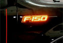 Image is representative of Recon Illuminated Fender Emblems.<br/>Due to variations in monitor settings and differences in vehicle models, your specific part number (264283AMBK) may vary.